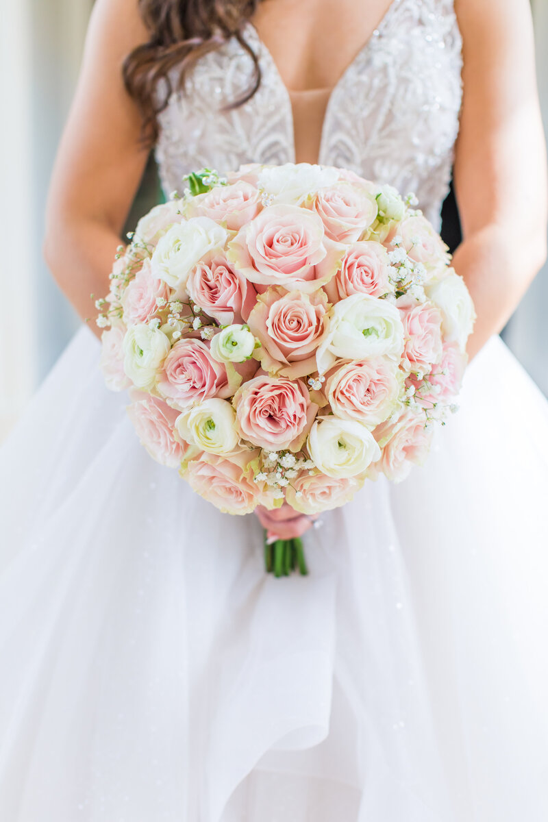 Disney Fairy Tale Wedding's bride holding her bridal bouquet with a Mickey Mouse diamond pin in the center.