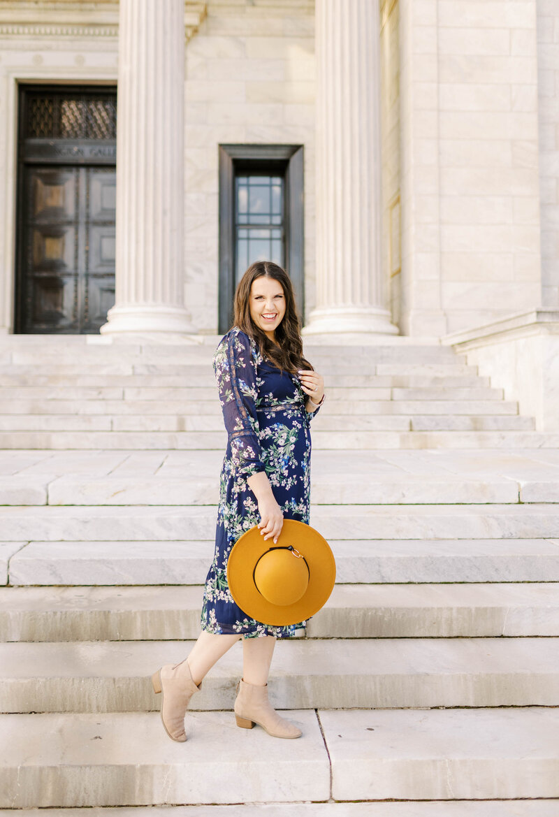 Elopement Photographer, a woman stands on the courthouse steps smiling, she holds a large hat