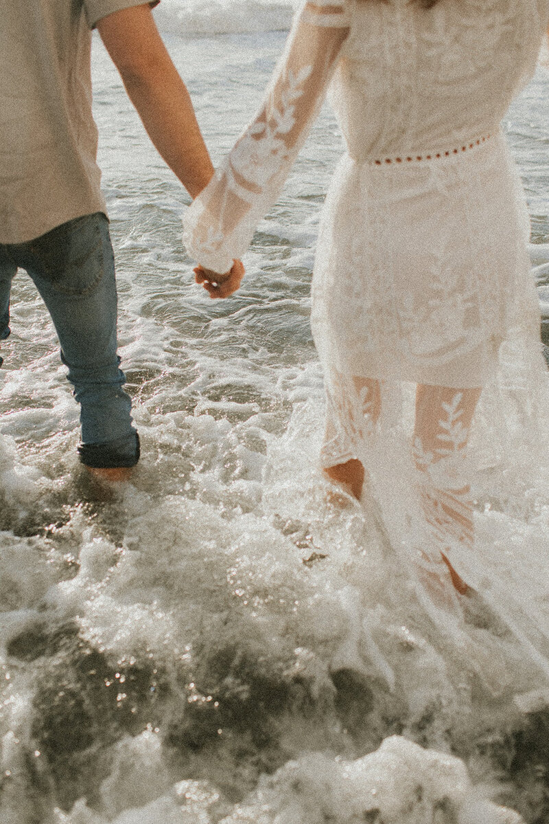couple laughing holding hands in sand dunes