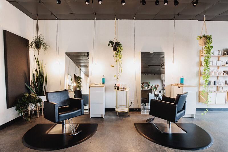 A hair salon featuring two styling stations with chairs and houseplants representing a salon chair rental.