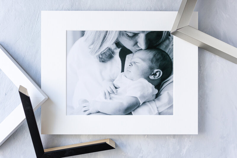 custom framing options for black and white portrait of mom kissing newborn baby