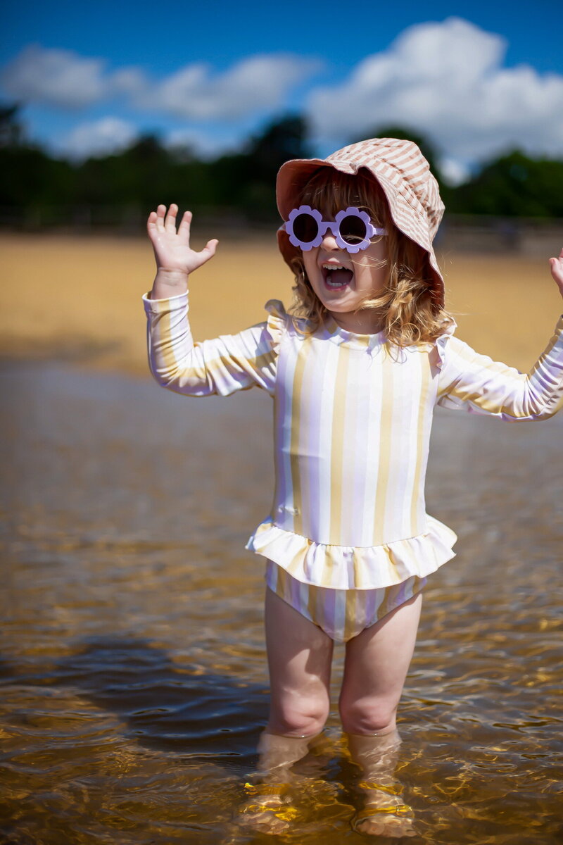 child splashing on beach  arms in the air in surprise