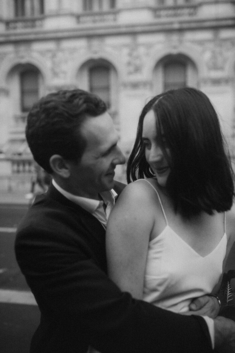 black and white photo,  bride is looking back at her man as her back rests against his chest, they look at each other and smile.