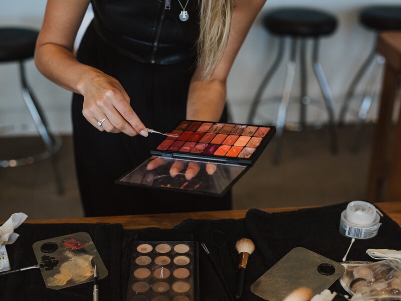 A Beauty Tribe makeup artist getting lipstick out of a lipstick palette.