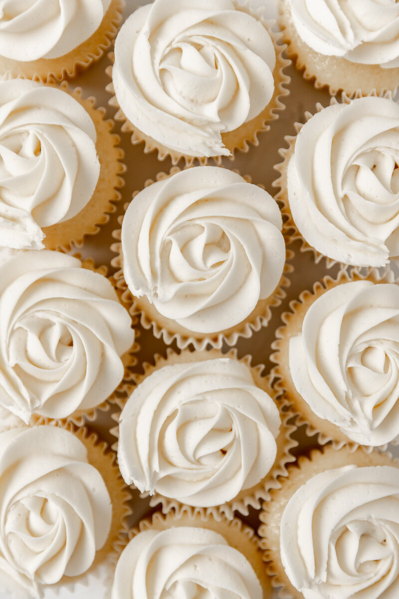 cupcakes decorate with white frosting in a rose design