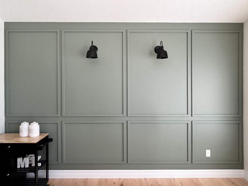 A sage green wainscotting accent wall with two black sconces