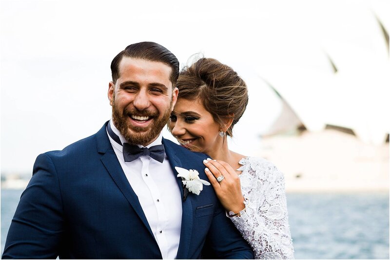 Bride and groom laughing together across the water from the Sydney Opera House in Australia
