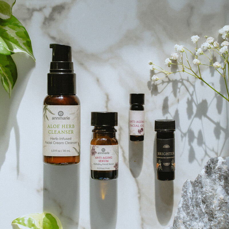 picture of some Annmarie Gianni skincare products against a white background with white flowers and green leaves