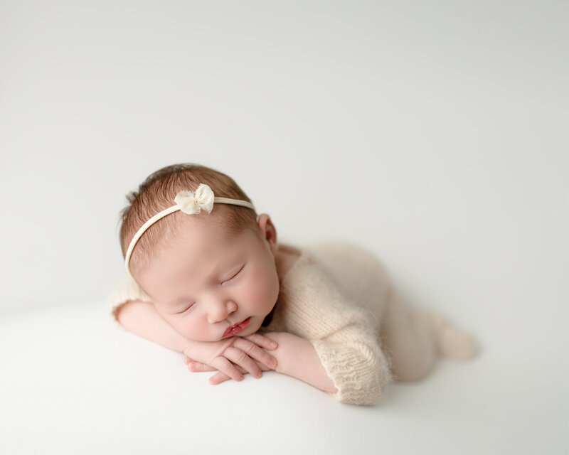 With her dainty bow and peaceful expression, this baby girl embodies the softness and grace of new life.