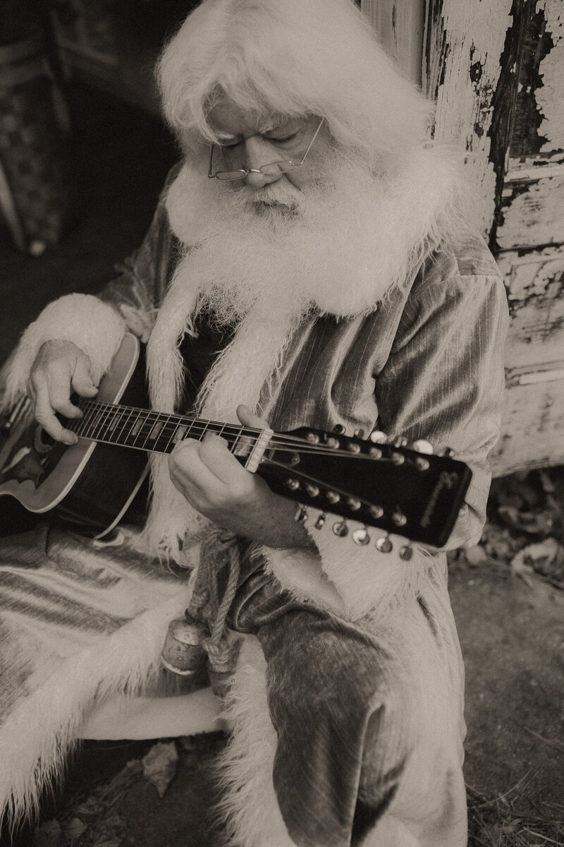 Santa sitting against a door frame and playing the guitar at Das Hinterhaus in Marietta, GA. 