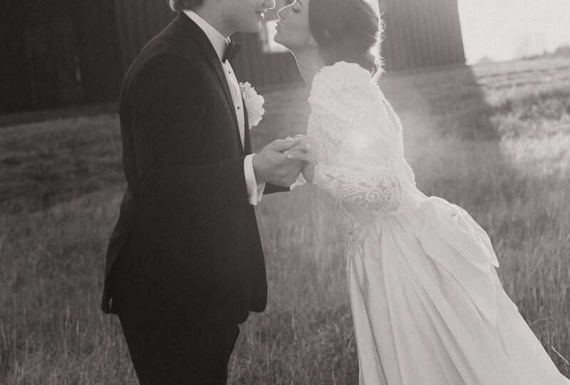 Bride and groom kiss in a field