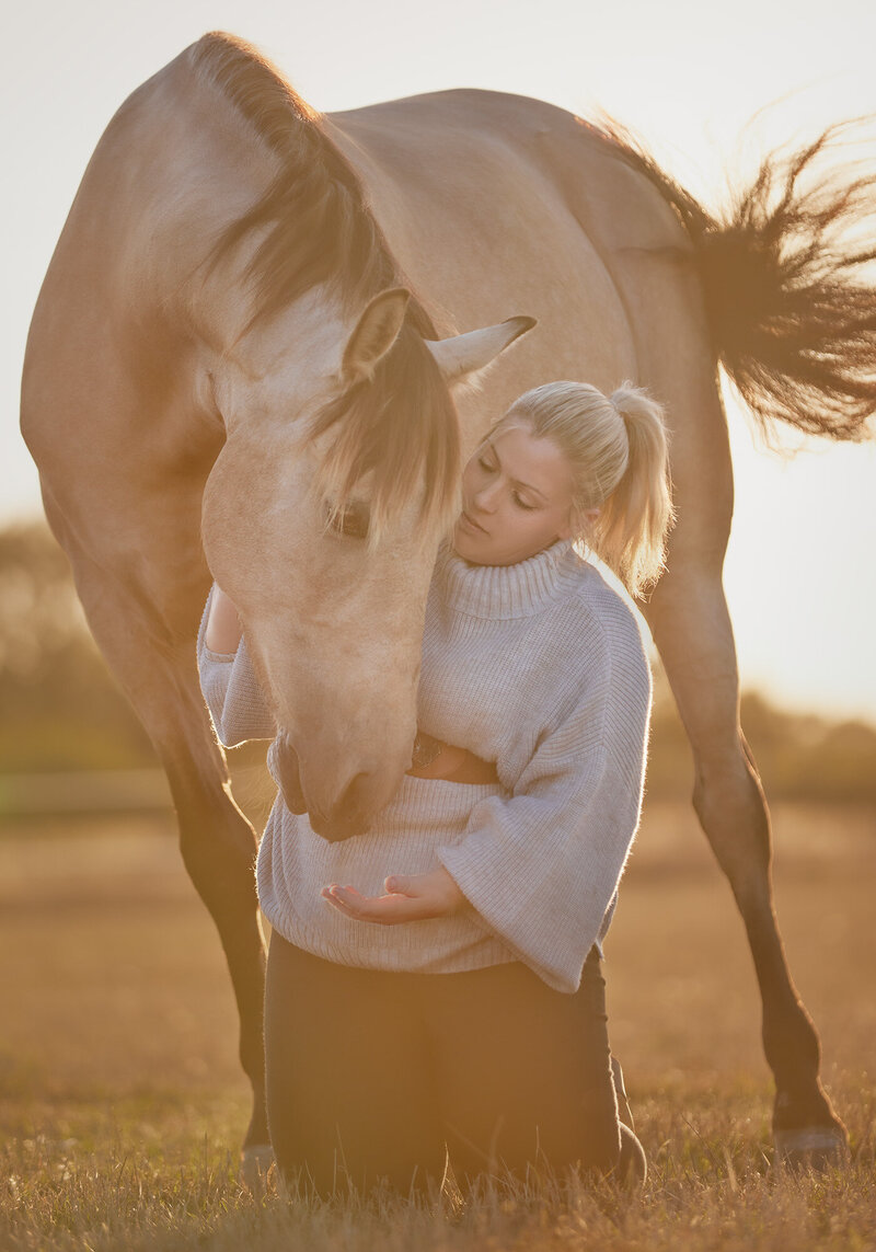Portrait of horse and owner taken on location in Aylsham by horse photographer Claire Howes. The owner is kneeling and the horse is bowing down to her.