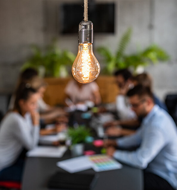 Small group at a table with a hanging lightbulb in focus in the foreground