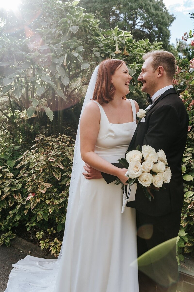 A married couple standing in front of trees at the botanical gardens Queensland