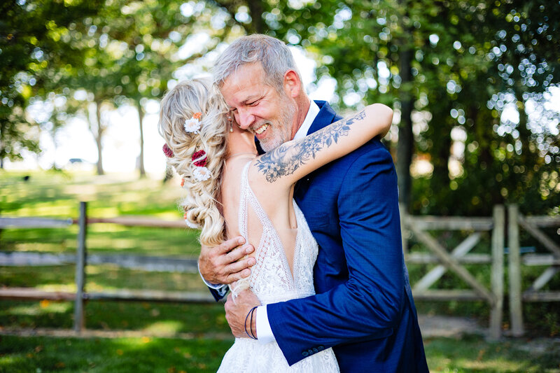 A father hugs the bride and smiles before the ceremony