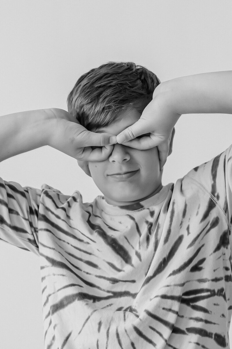 Boy in tie dye shirts makes silly face for black and white personality pictures with Kansas City Family Photographers.