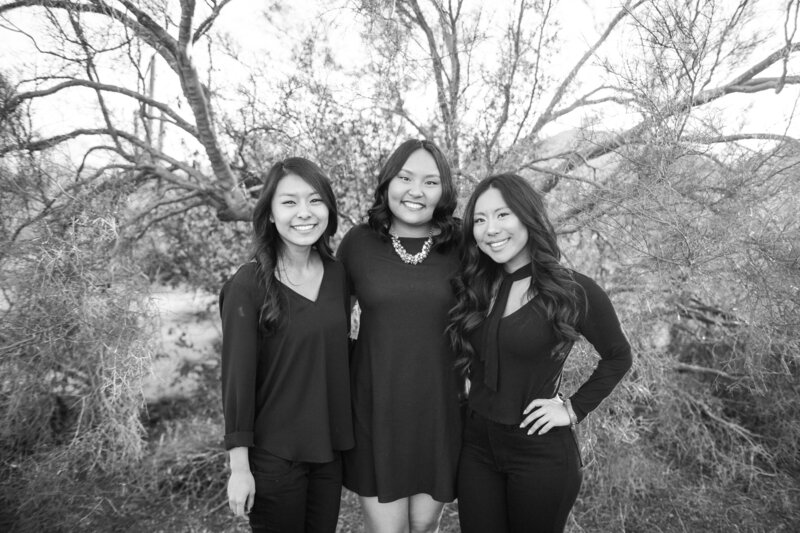 Three sisters pose for family shoot in front of bare tree..