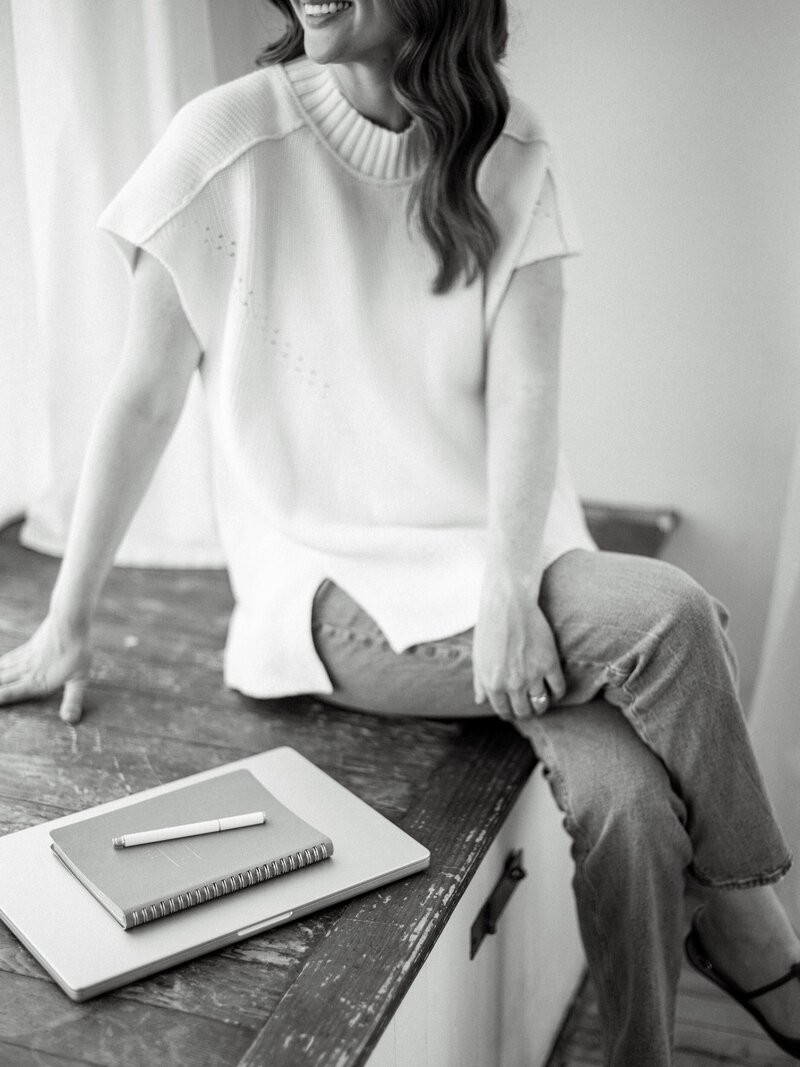 Woman holding laptop and glasses
