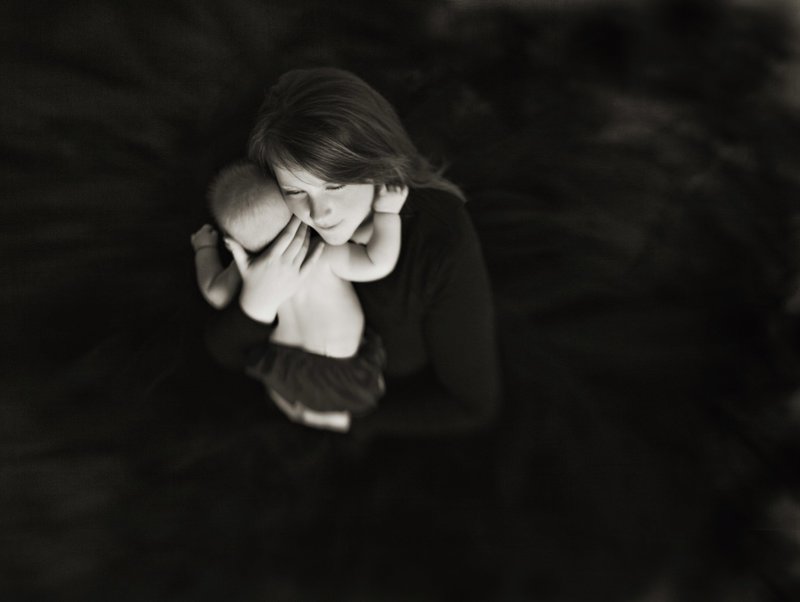 Tender portrait of a mom holding her baby wearing a black tulle  dress.