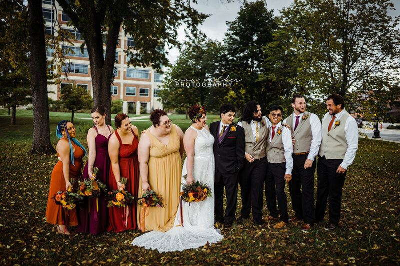 Wedding party talking to each other in a park during autium. 