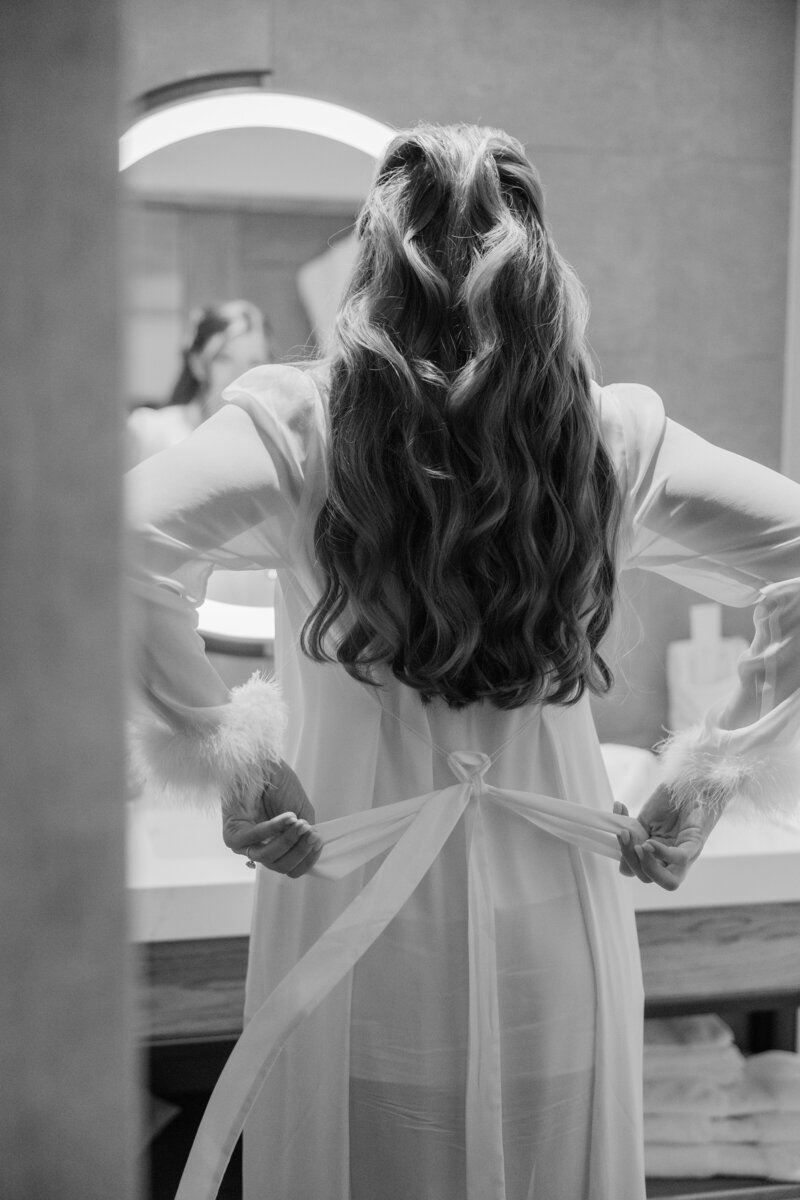 A black and white photo of a Bride tying her bridal robe at the Ben in West Palm Beach.