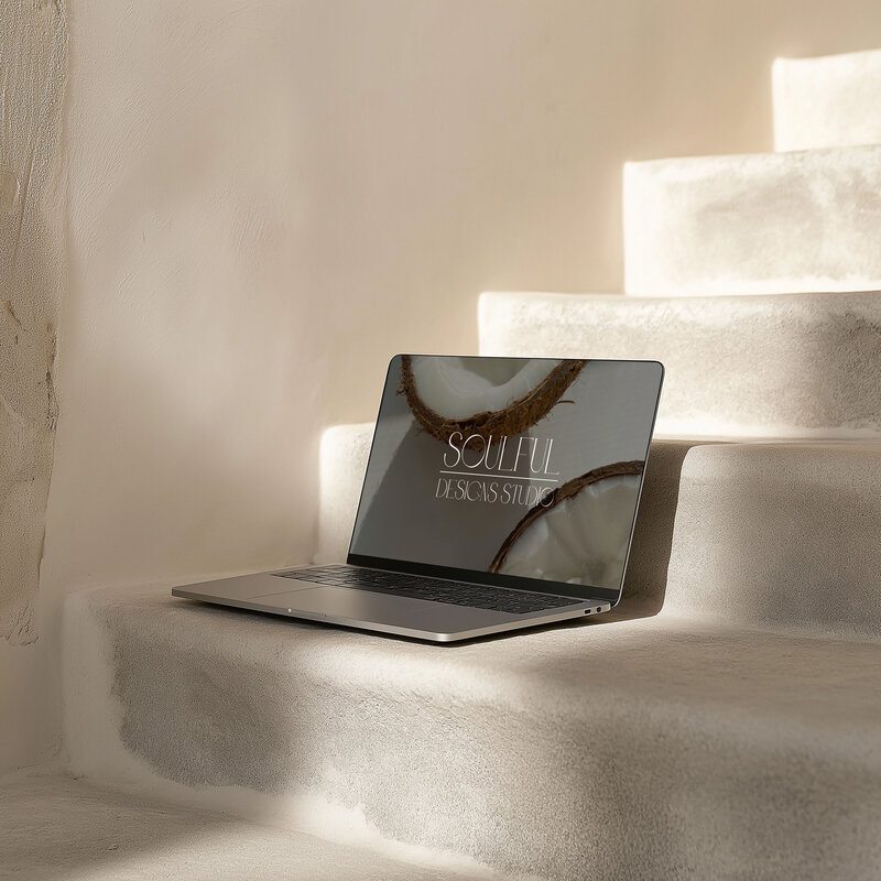 A laptop on beige rock stairs. On the screen a website from Soulful designs studio