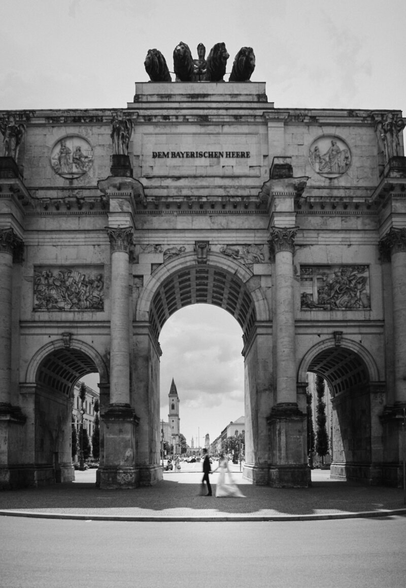 Brautpaarshooting am Siegestor. Das Hochzeitspaar läuft am Siegestor entlang.
