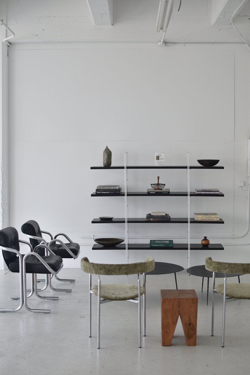 Aesthetic, sophisticated office with black and green chairs and open bookshelf