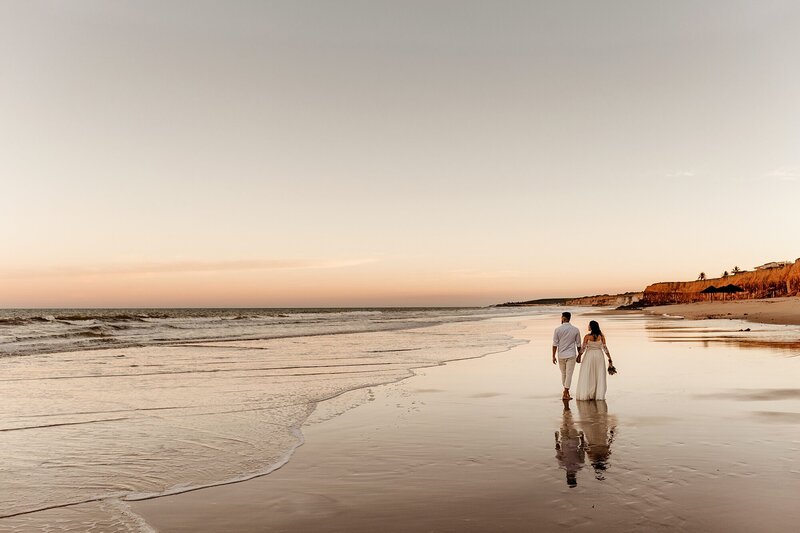 bride and groom walk along the beach at sunset in Bali