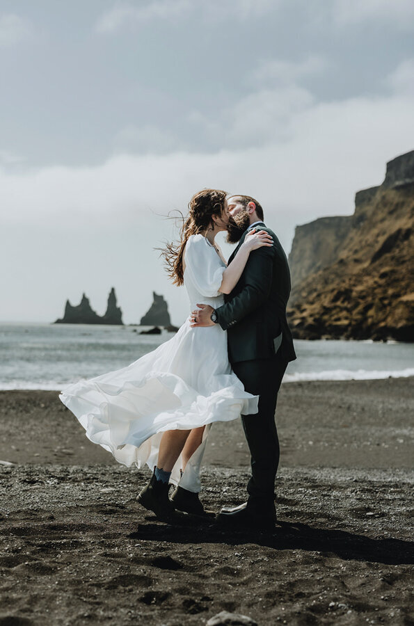 Bride and groom are kissing on their elopement day in Iceland on the Black Sand Beach