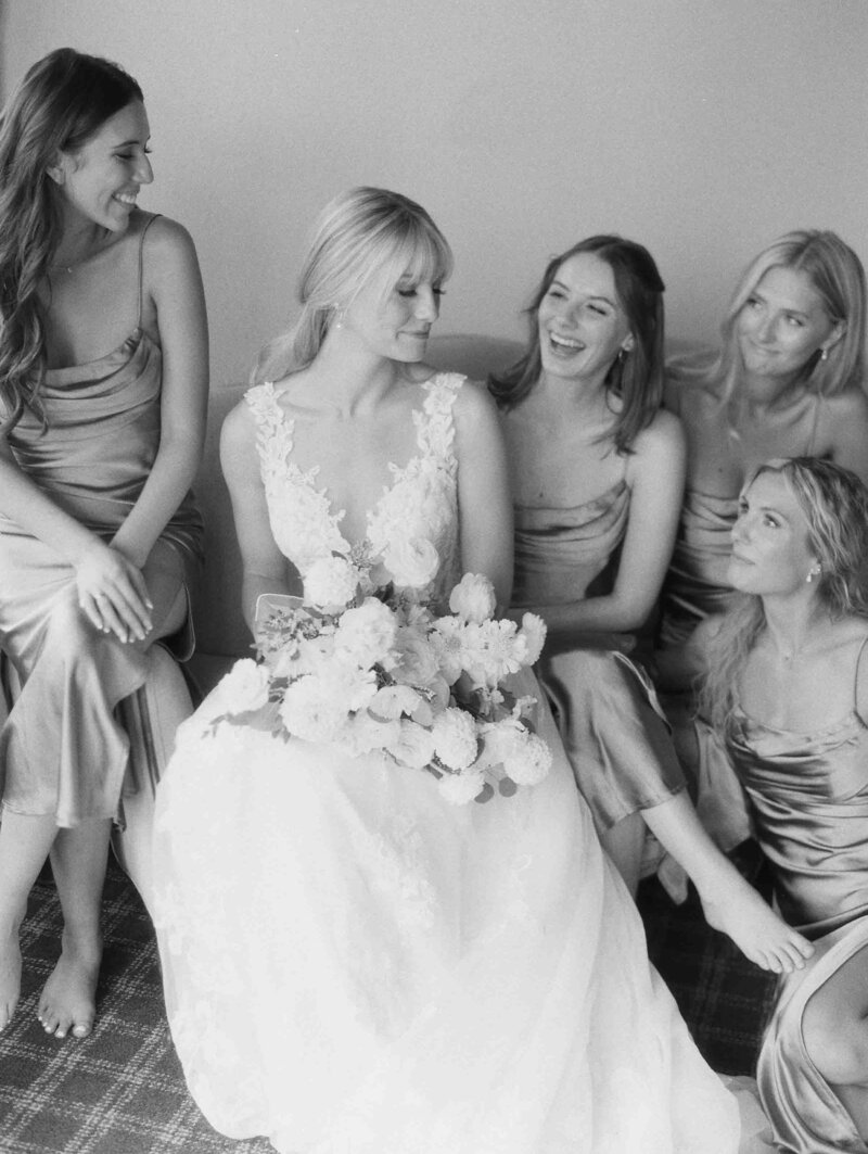 bride and her bridesmaids laughing at each other  in black and white