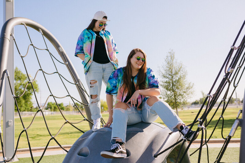 Two friends sitting on a playground laughing.