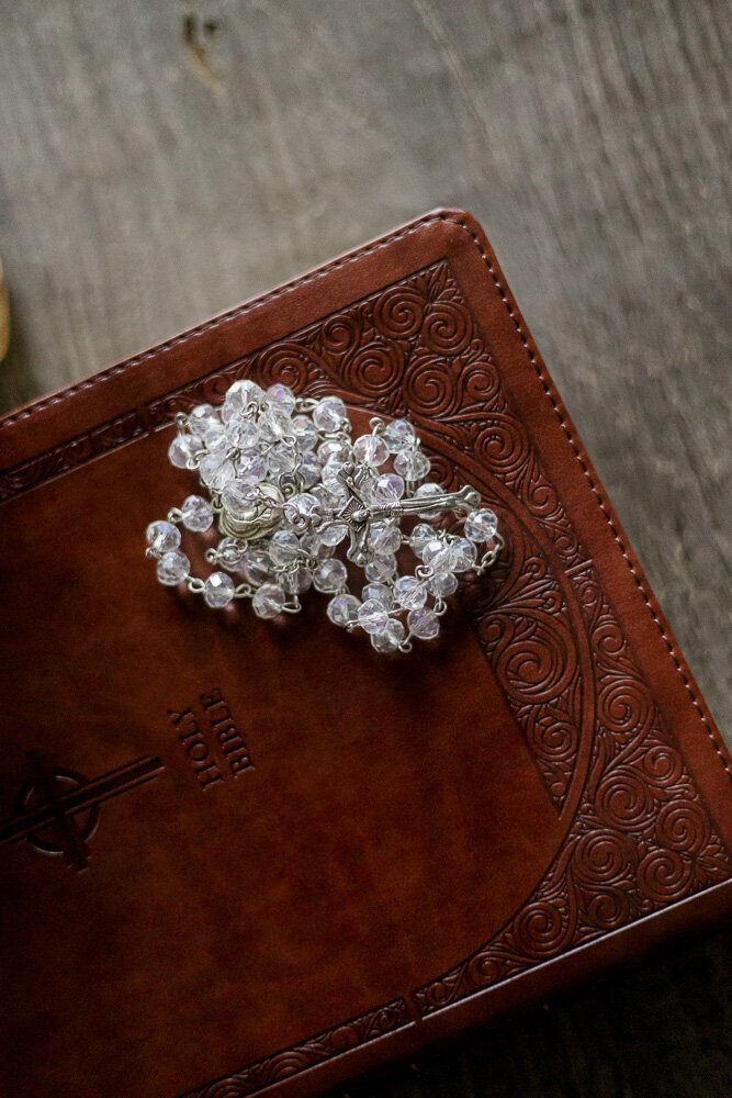 Catholic Rosary beads placed on top of a leather Bible