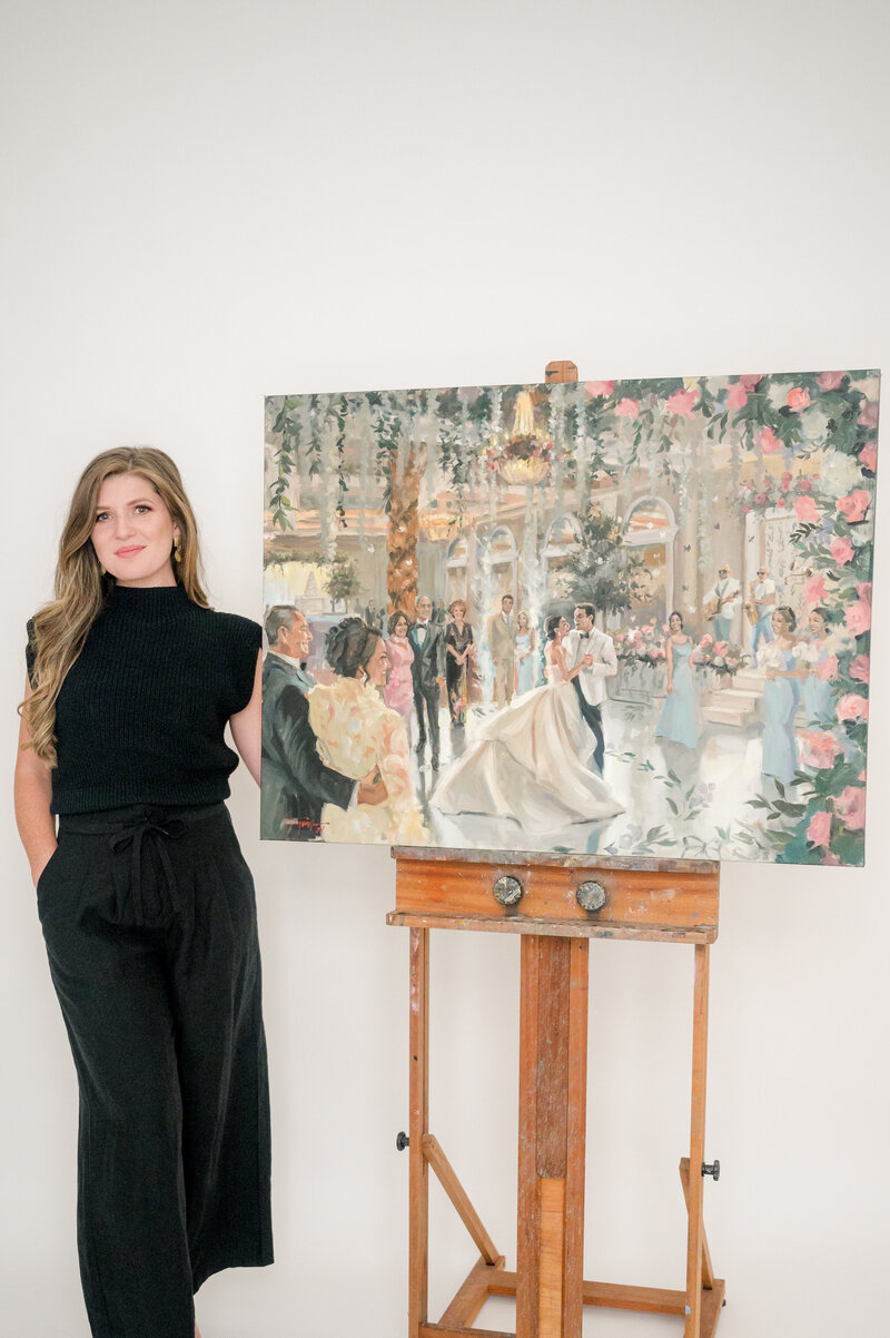 Stephanie Gaffney, owner of Torregrossa Fine Art, shows off large live wedding painting of couple dancing in floral ballroom