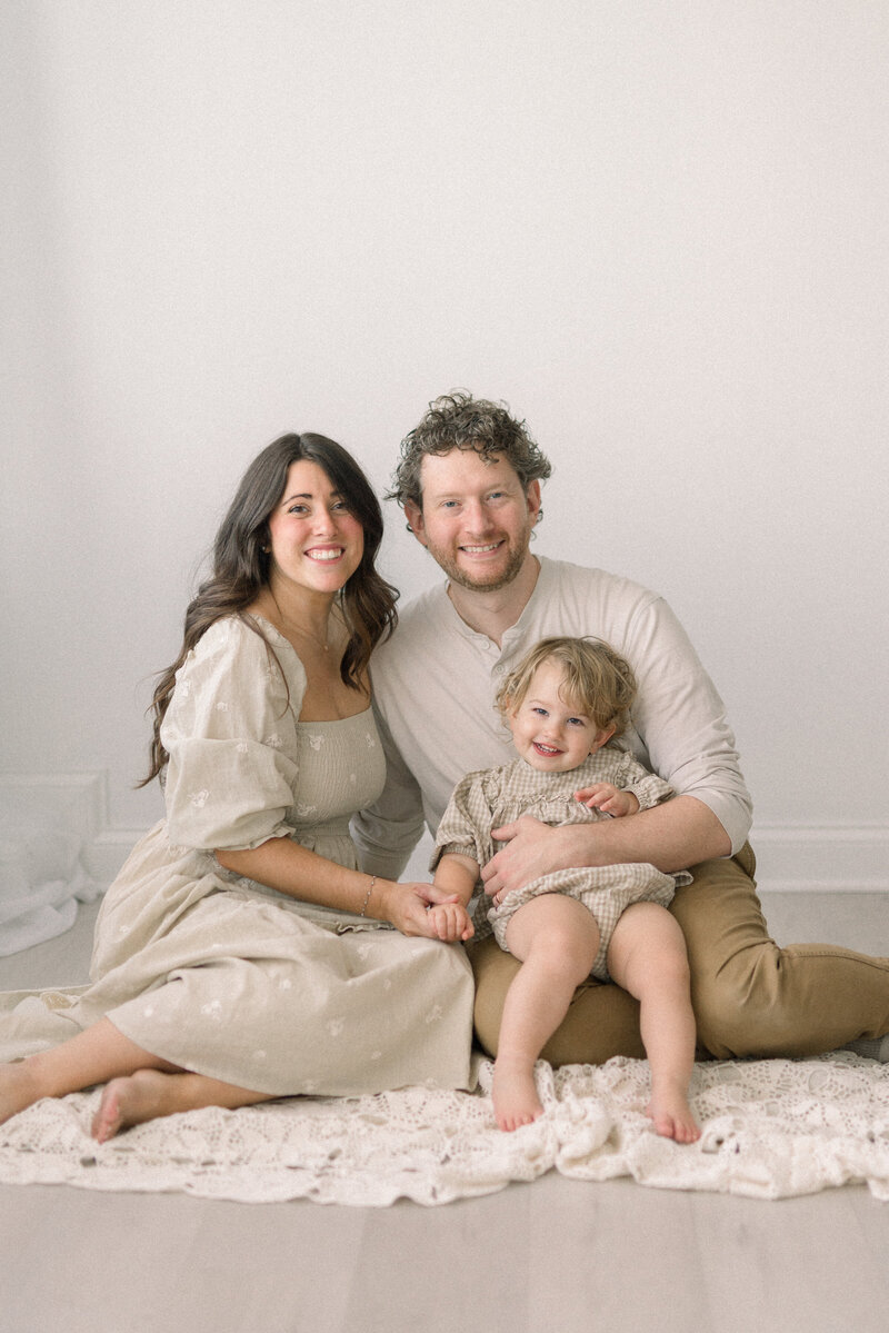 family sitting on floor in studio looking at camera knoxville tennessee newborn photographer