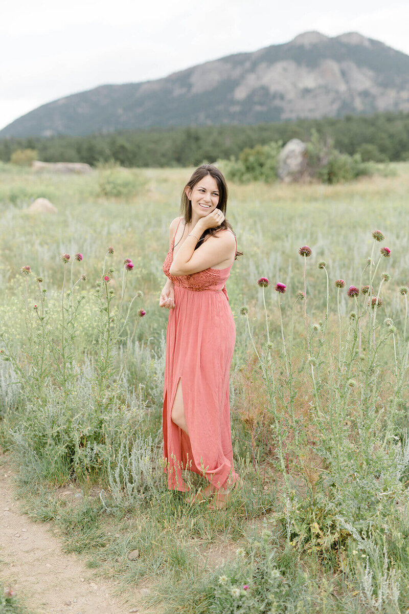 business strategy expert and Find Your Freedom Co founder Laura, standing in a field of wild flowers wearing a pink dress