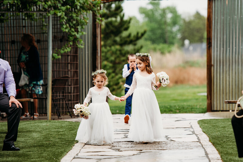 Flower girls holding hands and walking down the aisle