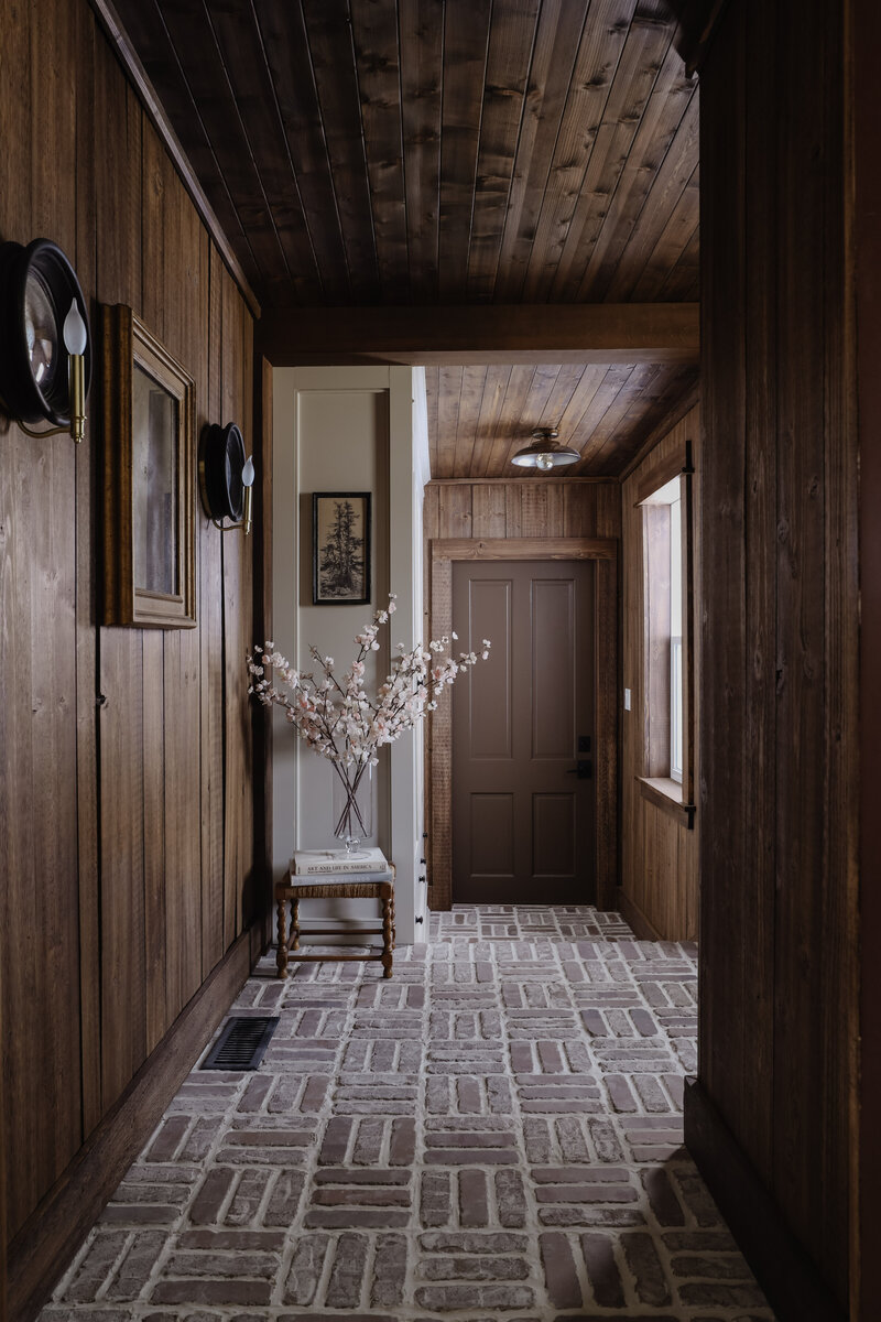 Laundry Room renovation by Nadine Stay. Rustic dark wood walls with basketweave brick floors. Moody laundry room before and after.