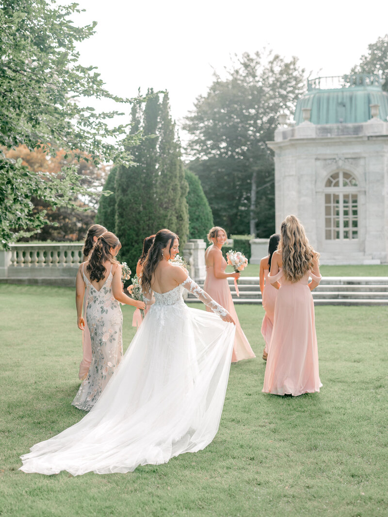 Bride and her bridesmaids walking away from the camera bride holding her dress