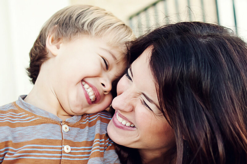 Mom and her son are cracking up laughing, faces really close together.