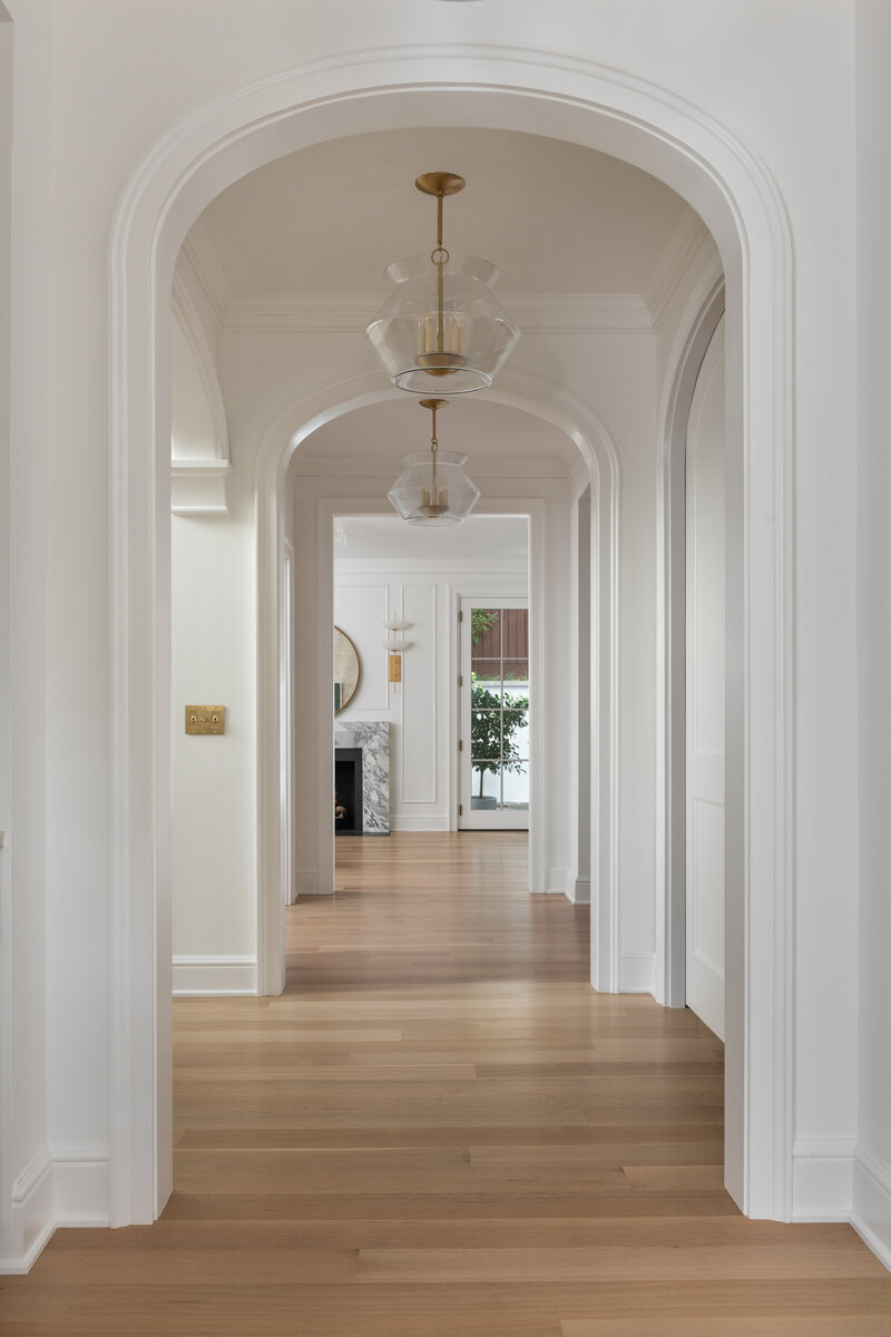 Bright white hallway with arched walkthroughs to living room