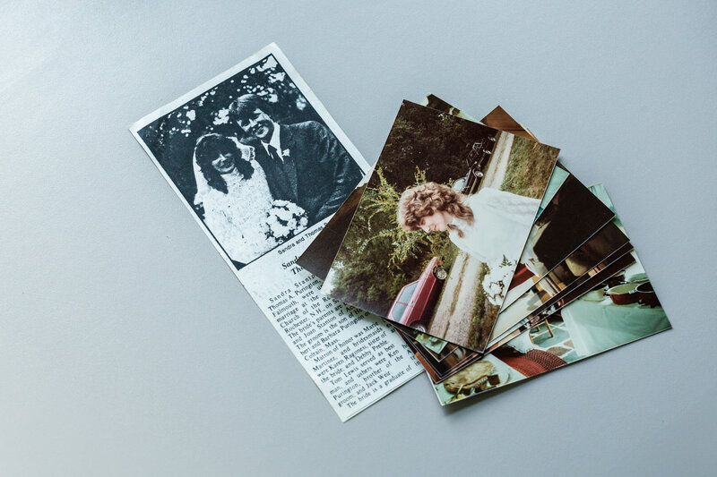 A scanned newspaper article alongside a stack of 4x6 wedding photos, prepared for album modernization.
