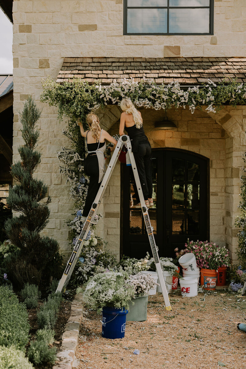 Two Nashville floral designers on a ladder working on a wedding ceremony feature