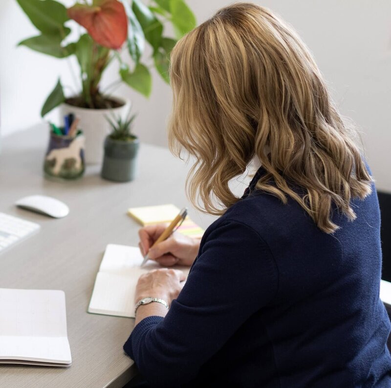 Back of Francine 's head  sitting at desk writing in notebook