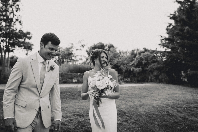 Candid black and white photo of a bride and groom laughing together after their Maine wedding ceremony.