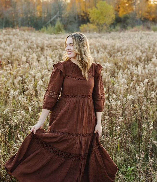 Top London Ontario photographer wearing a brown dress in a field of long grasses in the fall
