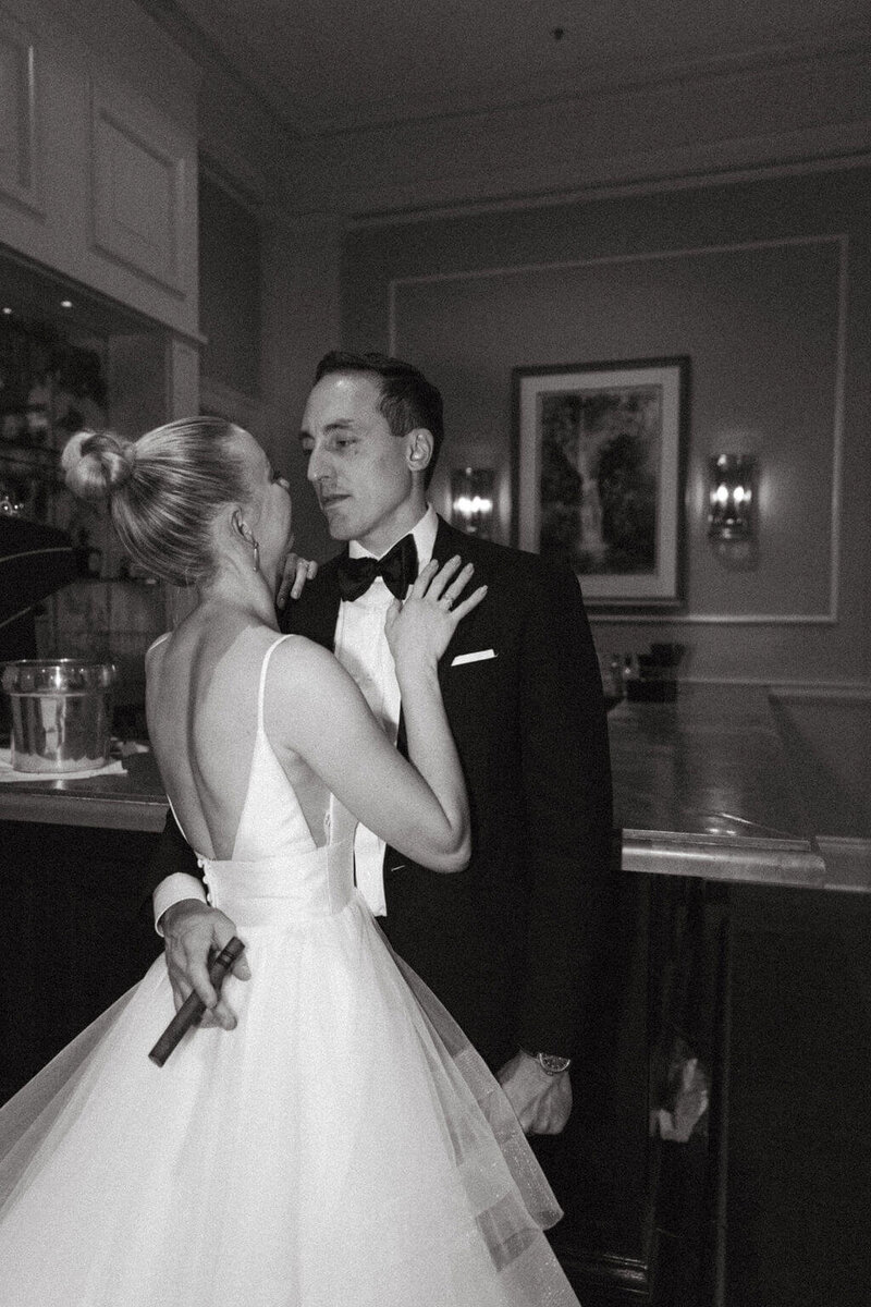 Couple in wedding attire looking at eachother while groom holds a cigar