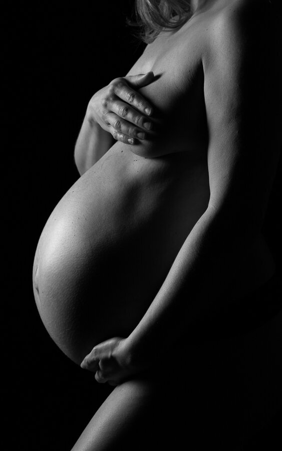 black and white closely cropped pregnant belly portrait. Created on a black background in the Insley Photography charlotte nc studio