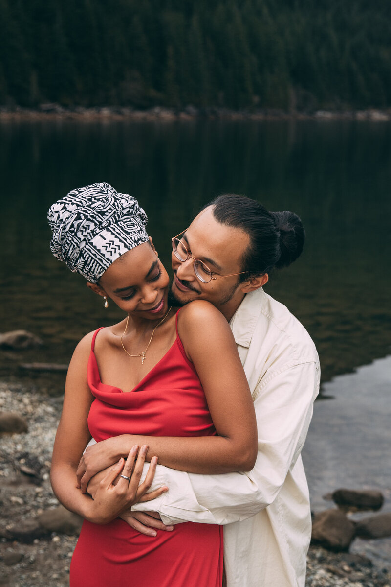 A couple in each others arms snuggled up by a mountain lake in Golden Ears Provincial Park