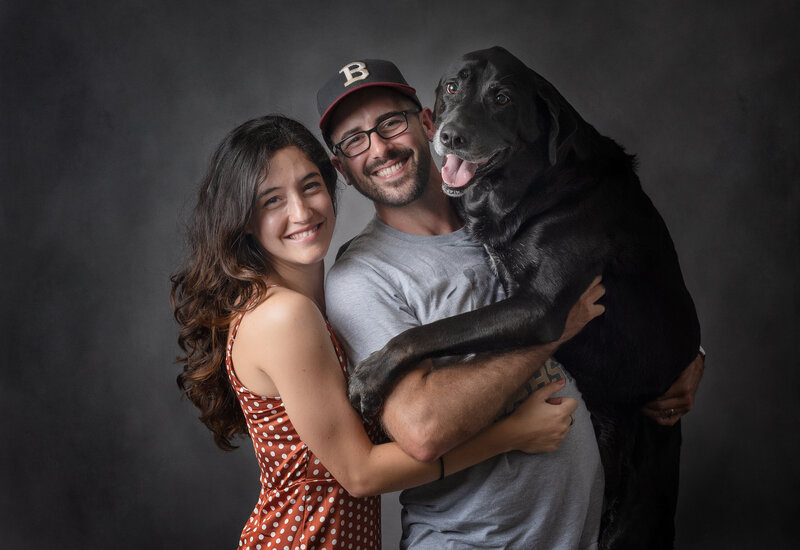 man woman holding a dog all smiling